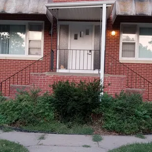 Crooked porch with untrimmed bushes!!