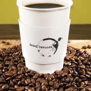 a cup of coffee surrounded by coffee beans