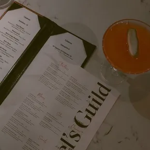 a menu and a drink on a table