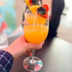a person holding a glass of orange juice