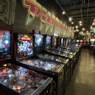 a row of pinball machines in a pinball arcade