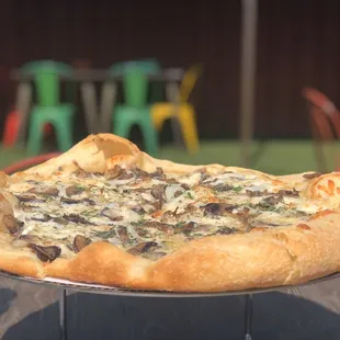 a pizza with mushrooms and cheese on a metal platter