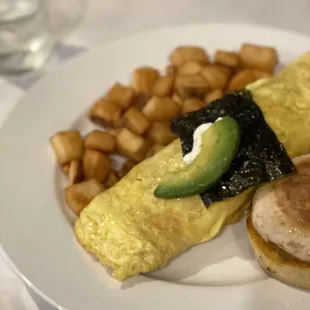 an omelet, eggs, potatoes, and avocado on a plate