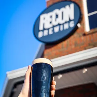 a hand holding a pint of beer