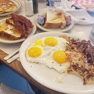 a breakfast of eggs, hash browns, bacon and toast