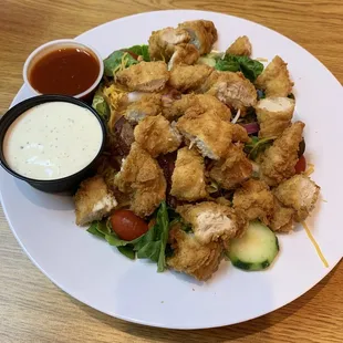 Chicken tender salad with side of ranch and Buffalo sauce.