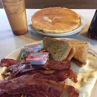 a plate of bacon, eggs, toast, and pancakes