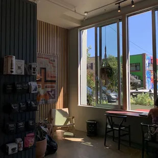 Indoor seating area with comfy chairs, tables and big windows with a view of beautiful outdoor murals.