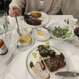 Ribeye w baked potato and iceberg lettuce salad   New York Strip with brussel sprouts and grits