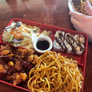 Bento box with General Tso, lomein, ginger salad, and crunchy roll.