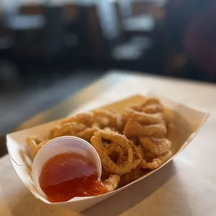a basket of deep fried squids with ketchup