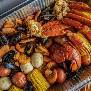 crab legs, corn, potatoes, corn on the cob
