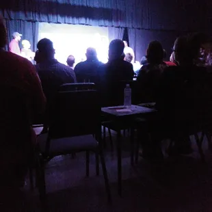 a group of people sitting in front of a screen