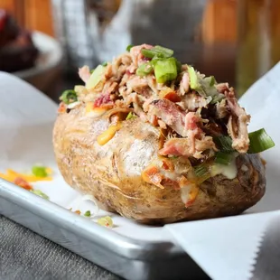 Idaho Stuffed Pig. A BIG OL&apos; smoked potato stuffed with Carolina Pulled Pork, cheddar cheese, green onion, butter and sour cream.