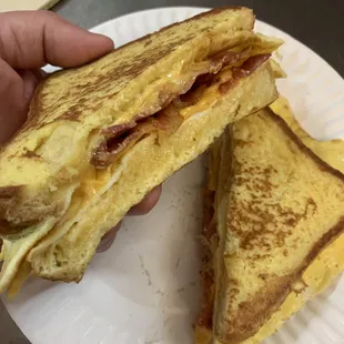 a person holding a sandwich on a paper plate