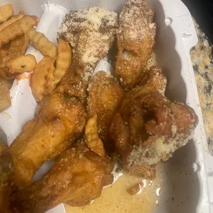 fried chicken wings and french fries in a styrofoam container