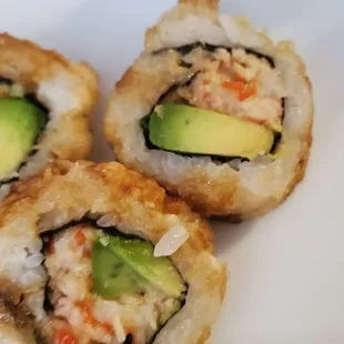 three sushi rolls on a white plate