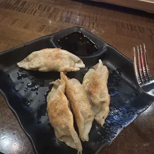 three dumplings on a black plate