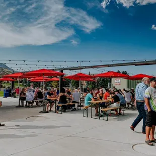 a crowd of people sitting at tables under red umbrellas