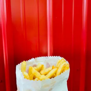 a hand holding a bag of french fries