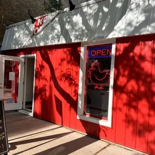 open sign in front of a red building