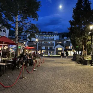 people sitting at tables outside a restaurant at night