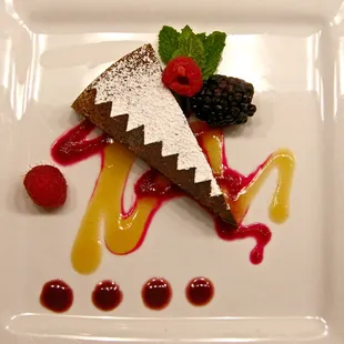 Flourless chocolate pinon torte served with a peach honey sauce, prickly pear syrup, and chokecherry sauce with seasonal fruit.