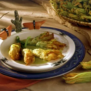 Seasonal squash blossoms stuffed with goat cheese, tomatoes, chiles, and sweet onions and fried in a light batter.