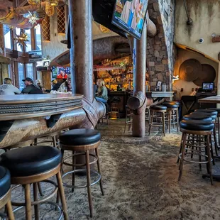 a bar with stools and a television