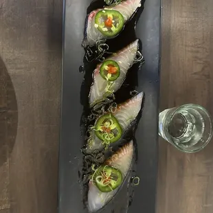 three pieces of fish on a black plate