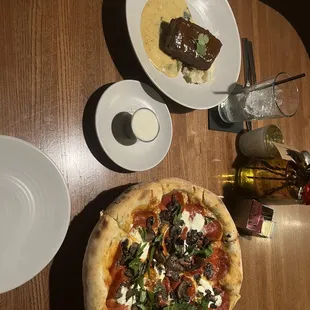 a table with a pizza and plates of food