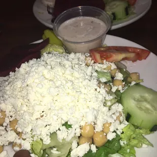 a plate of salad with cucumbers, tomatoes, and feta cheese