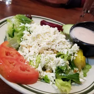 a plate of salad with a side of dressing