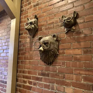 three animal heads mounted on a brick wall