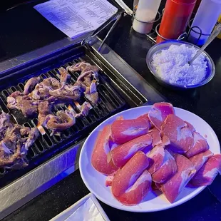 a plate of raw meat on a grill