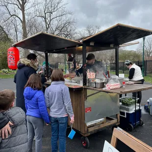 a group of people standing around a food cart
