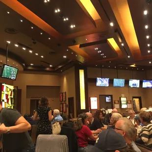 A nice poker room with a lot of tables and TVs.