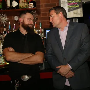 two men standing in front of a bar