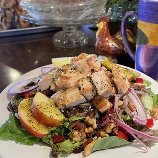 a plate of salad with chicken and apples