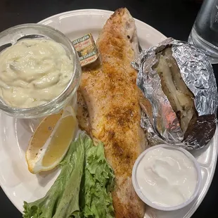 Walleye with a baked potato and tartar sauce.