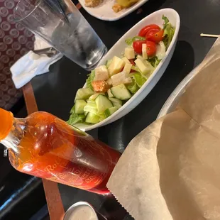 a salad and a bottle of hot sauce