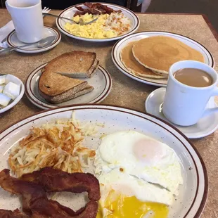 a breakfast of eggs, bacon, toast, pancakes and coffee