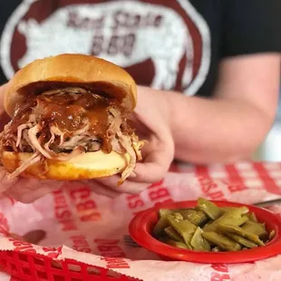 a person holding a pulled pork sandwich