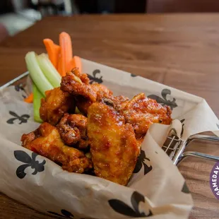 a basket of chicken wings with carrots and celery