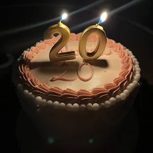 a birthday cake with two lit candles