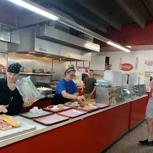 three people preparing food in a kitchen