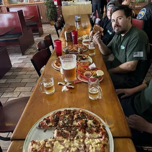 a group of people sitting at a table eating pizza