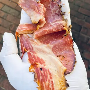  hand holding a piece of bacon