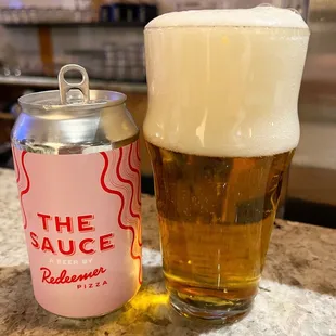 a glass of beer and a can of sauce