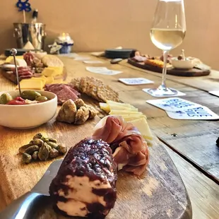 a wooden board with meat, cheese, and olives